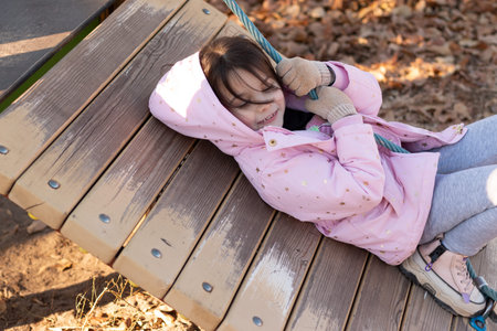 A small child with long hair gathered in a ponytail against the background of a blue sky in warm...