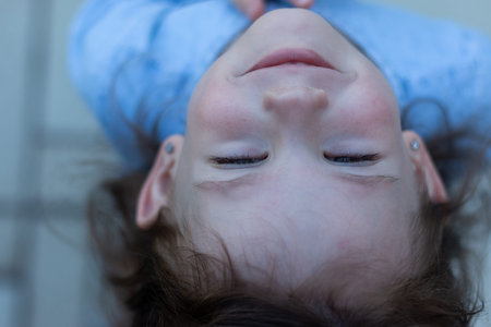 A little beautiful preschooler girl stands in a denim blue dress. Upside down photo of a cute babyの写真素材