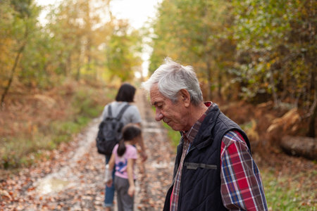 Senior man hiking with his family in autumn forest, shallow depth of fieldの写真素材
