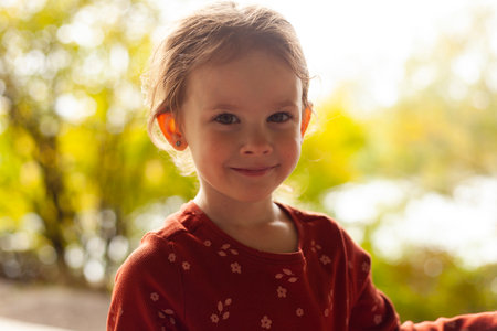 Portrait of a cute little girl in a red dress on the natureの写真素材