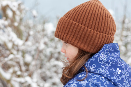 Portrait of a beautiful girl in a knitted hat on a background of the winter forestの写真素材