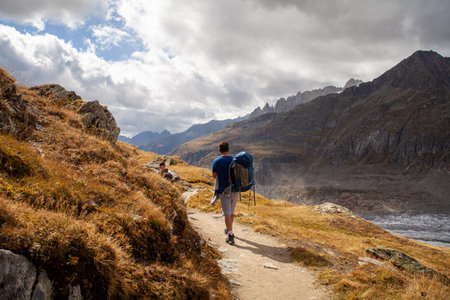 Hiker with a backpack on a mountain route in the Swiss Alpsの写真素材