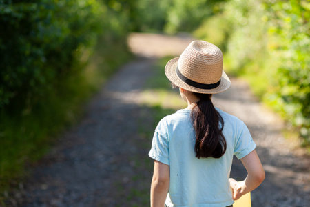 Young woman wearing a straw hat in the park. back view.の写真素材