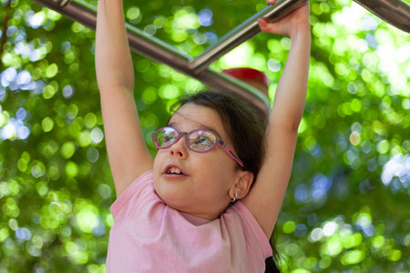 Asian little girl playing on the playground in the park. Kid having fun outdoors.