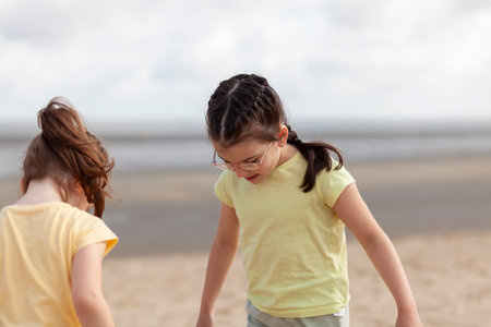 Portrait of two little girls playing on the beach at the day timeの写真素材