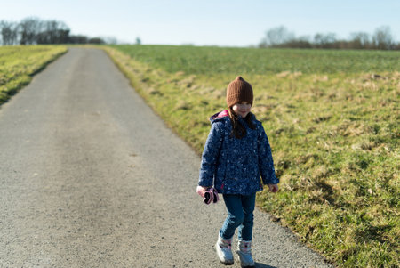 Cute little girl walking on a country road on a sunny dayの写真素材