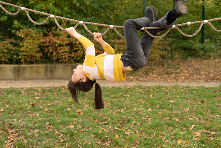 Teenage girl having fun on a rope playground in autumn park.の写真素材