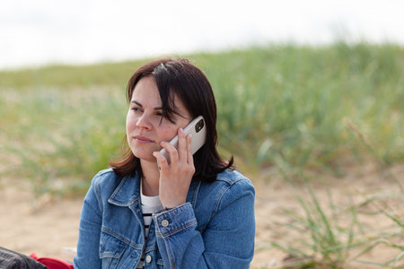 Young woman talking on mobile phone on the beach of the Baltic Sea