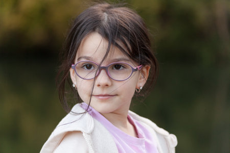 Portrait of a beautiful little girl with glasses in the park.の写真素材