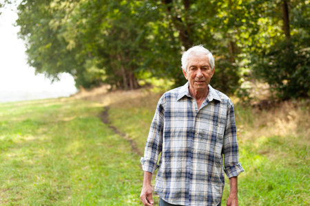 Portrait of senior man standing in the park on a sunny dayの写真素材