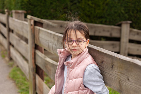 Portrait of a cute little girl in a pink jacket and glasses