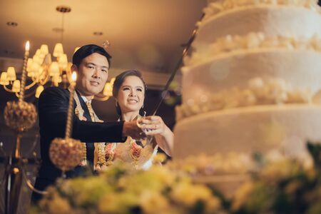 Bride and groom are cutting cake for celebration on their wedding dayの写真素材