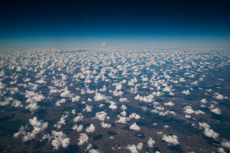 Earth surface viewed from airplane. Nature landscape from aerial view. White clouds and blue sky up above the earth. Nature and landscape image.の写真素材