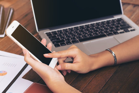 Business woman using mobile phone or smart phone to communicate business partner. Laptop computer...