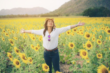 Happy woman in sunflower field smiling with happiness due to healthy food. Happy people, health care and agriculture business concept. Happy farmer or farm worker in sunny day at sunflower field.の写真素材