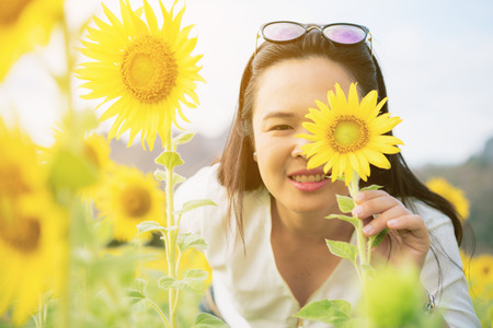 Sunflower and a woman hiding behind it. Selective focus at woman's eye.の写真素材