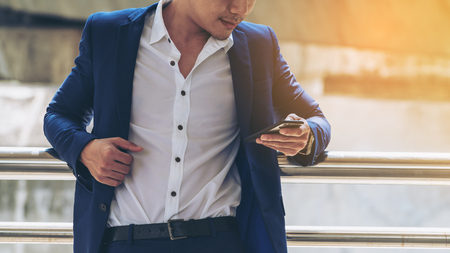 Business man using smartphone in the city background. Concept of business phone call, communication, phone message, phone communication technology.の写真素材