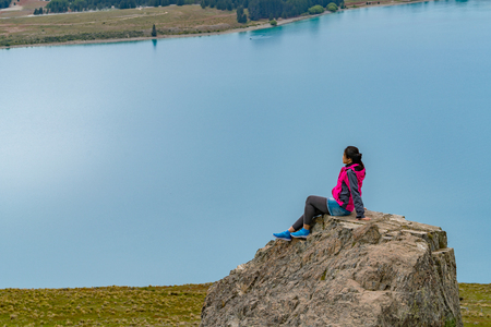 Woman traveller enjoys scenic view of lake Tekapo landscape in New Zealand.の写真素材