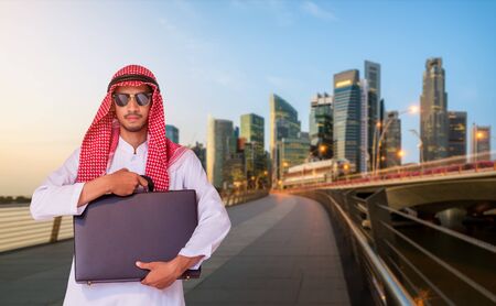 Arab man holding business briefcase in modern city. Concept of overseas international business of Arab businessman.の写真素材