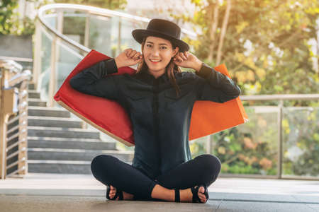 Happy woman with shopping bag sitting on the floor.の写真素材
