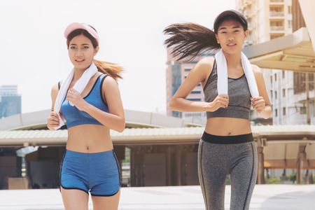 Two healthy woman running in the city background. Concept of women fitness, healthy urban lifestyle and urban running.の写真素材