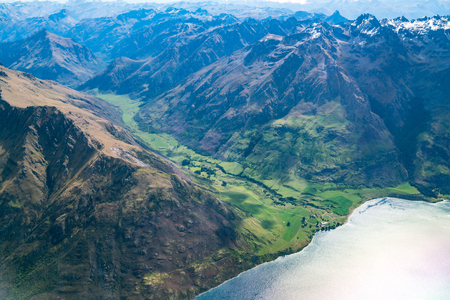 Aerial view of mountain ranges and lake landscape. Panoramic shot from airplane flying above mountains near Lake Wakapitu in Queenstown, New Zealand.の写真素材