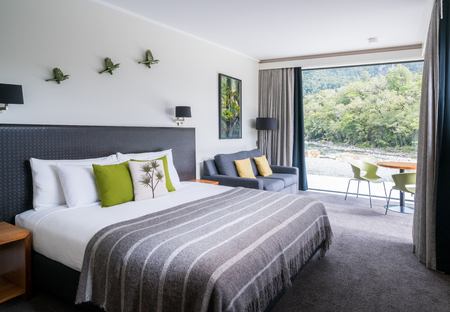 Milford Sound, New Zealand - Dec 7, 2016: Luxury bedroom interior decoration with nature scenic window look out at Milford Sound Lodge, accommodation in Milford Sound, Fiordland, New Zealand.のeditorial素材