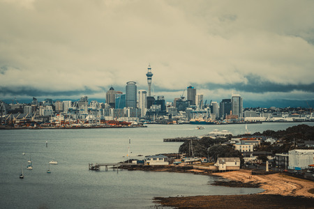 Auckland city skyline, New Zealand, with fishing wharf, city center and Auckland Sky Tower in cloudy day. Vintage color filter.の写真素材