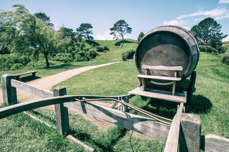 Vintage-style image of wine barrel on cart against green grass field in countryside agriculture landscape background. Organic food, winery and alcohol drinks product industry.の写真素材