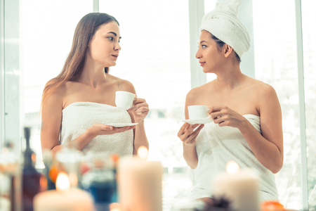 Two women drinking tea or herbal drinks while having conversation in luxury day spa. Wellness, leisure and healthcare concept.の写真素材