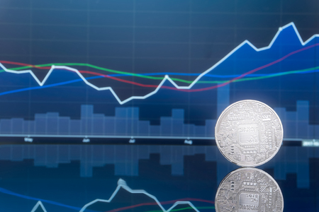 Initial coin offering (ICO) and digital money investing concept - Physical metal digital coins with blue global trading exchange market price chart in the background.の写真素材
