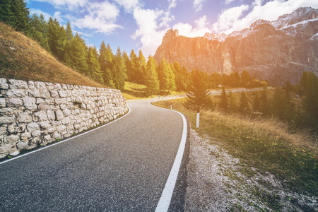 Beautiful mountain road with trees, forest and mountains in the backgrounds. Taken at state highway road in Passo Gardena, Sella mountain group of Dolomites mountain in Italy.の写真素材