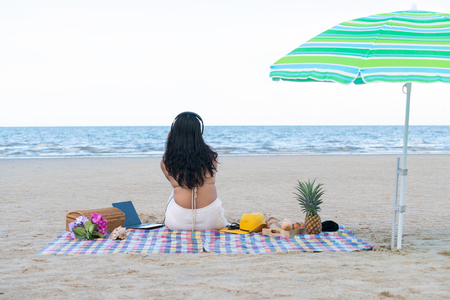 Woman in bikini is on vacation sitting on the beach in summer. Tropical beach travel lifestyle.の写真素材