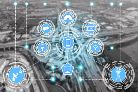 Smart city wireless communication network with graphic showing concept of internet of things ( IOT ) and information communication technology ( ICT ) against modern city buildings in the background.の写真素材