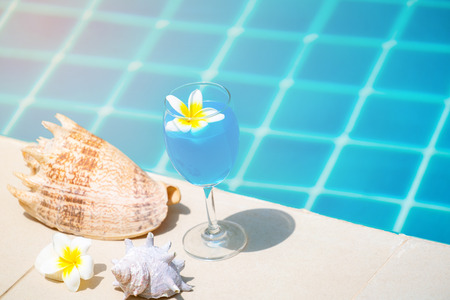 Summer concept - Glass of cocktail at swimming pool in luxury hotel resort with other summer accessories.の写真素材