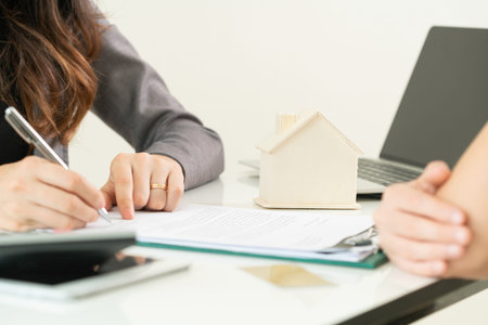 Client signs document regarding real estate activity next to lawyer or real estate agent sitting at...
