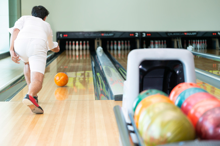 Young man playing bowling at the sport club.の写真素材