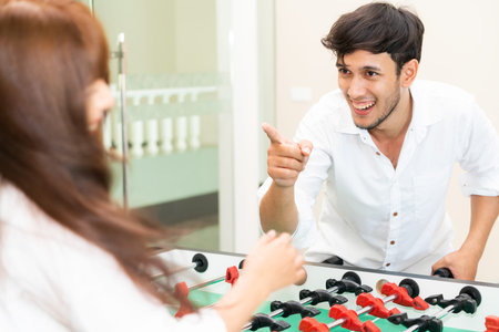 Happy young man playing foosball table soccer with girlfriend. Couple recreation and lifestyle.
