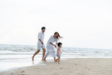 Happy family of father, mother and kids goes vacation on a tropical sand beach in summer.の写真素材