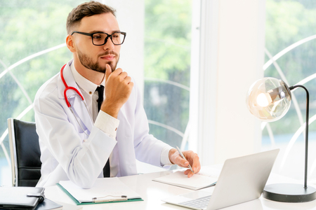 Male doctor works at office desk in hospital. Healthcare and medical service concept.の写真素材