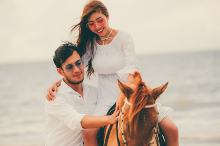 Young couple goes honeymoon horse riding on the beach in summer vacation.の写真素材