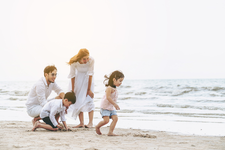 Happy family of father, mother and kids goes vacation on a tropical sand beach in summer.の写真素材