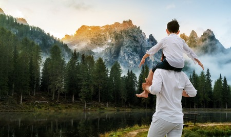 Happy father carrying his son on shoulders is on vacation and escape to nature.の写真素材