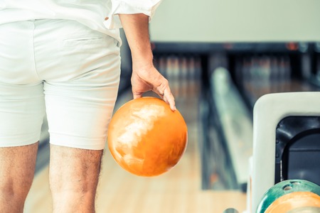Young man playing bowling at the sport club.の写真素材