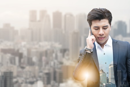 Double exposure image of businessman using mobile phone with modern business buildings and cityscape in the background. Digital innovation and technology disruption concept.の写真素材