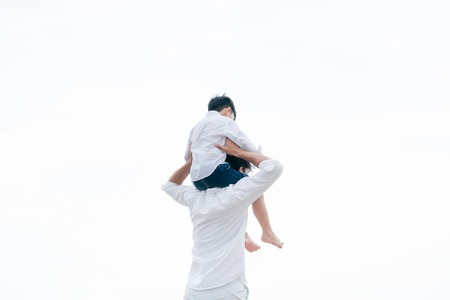Happy father carrying his son on the neck on a tropical sand beach in summer.の写真素材