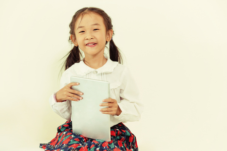 Little happy kid on white background with tablet computer. Childhood lifestyle.の写真素材