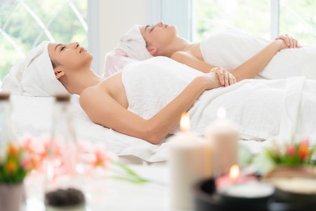 Relaxed young woman lying on spa bed prepared for facial treatment and massage in luxury spa resort. Wellness, stress relief and rejuvenation concept.の写真素材