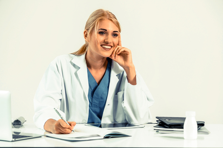 Woman doctor in hospital or healthcare institute working on medical report at office table.の写真素材