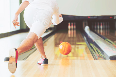 Young man playing bowling at the sport club.の写真素材